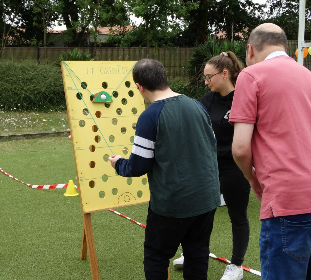 Les Résidents du centre d'habitat de d'aizenay jouent à des jeux d'adresse en bois. Le jeu s'appelle le Gruyère, a l'aide de ficelles, il faut faire monter une balle sur une planche en évitant les trous.